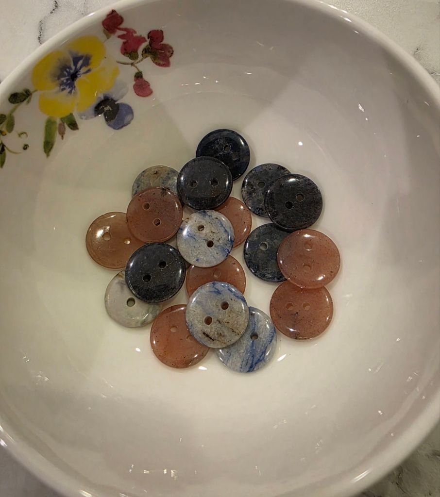 a bowl of buttons, three types, made of stone.
